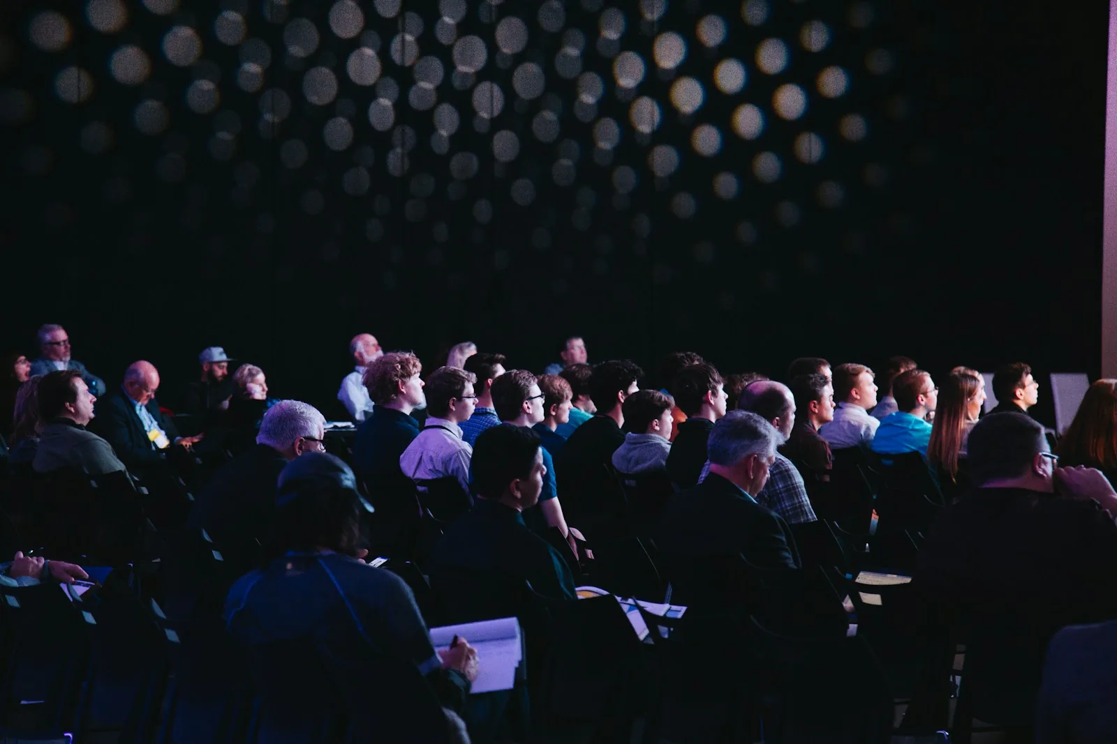 An audience seated in a darkened conference hall